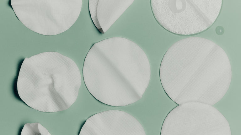 White circular cotton pads on a green background