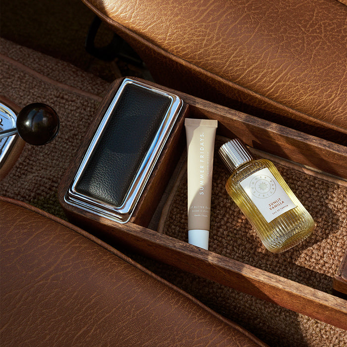 Perfume bottle and tube of cream on a wooden tray with leather surface